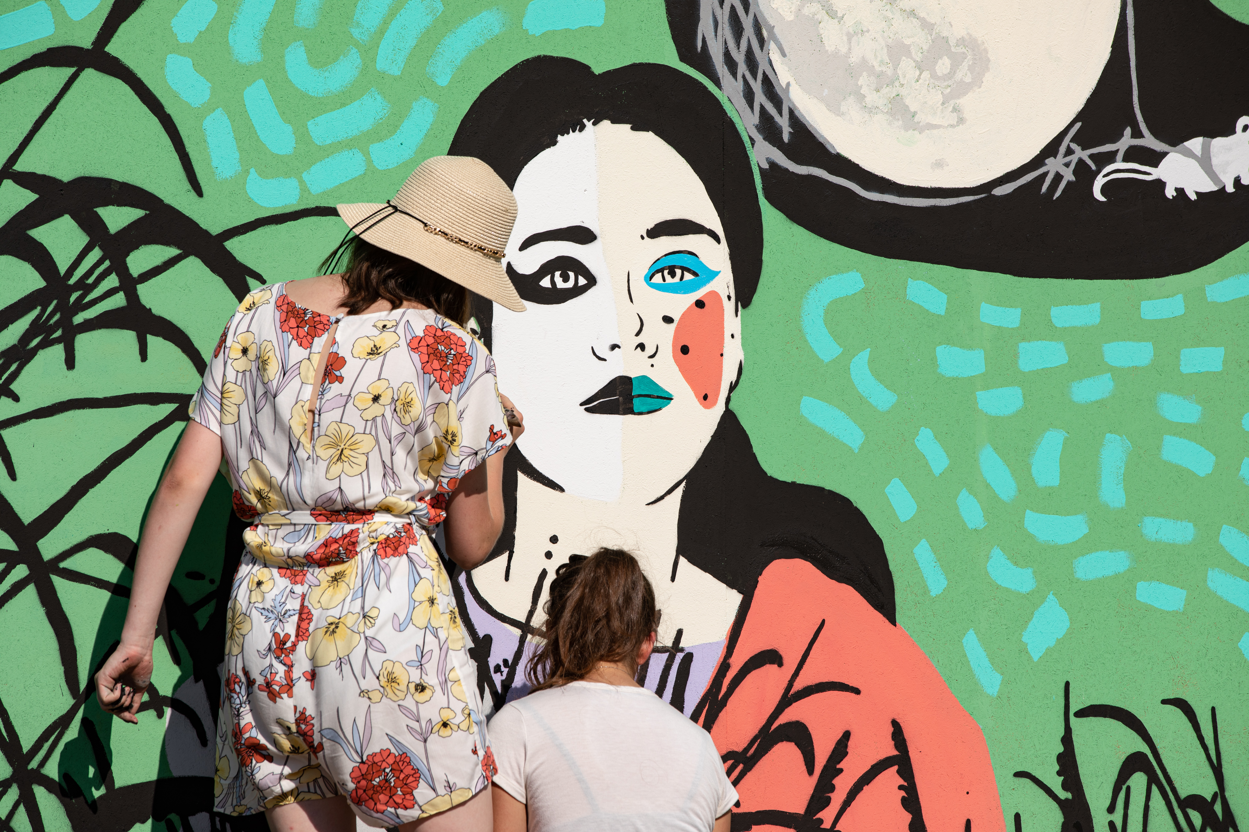 Mural na Łące Leśmiana. Dwie osoby malują szczegóły kobiecej twarzy.