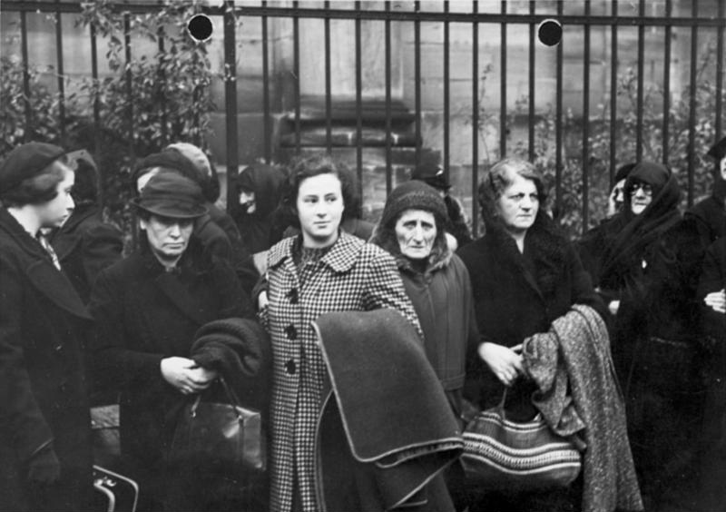 Czarno-białe zdjęcie. Grupa żydowskich kobiet stoi przed bramą.