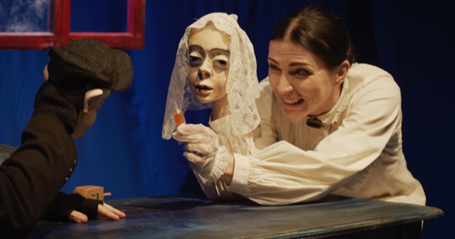 Spektakl w Białostockim Teatrze Lalek. Aktorka trzyma pacynkę przedstawiającą twarz kobiety.
