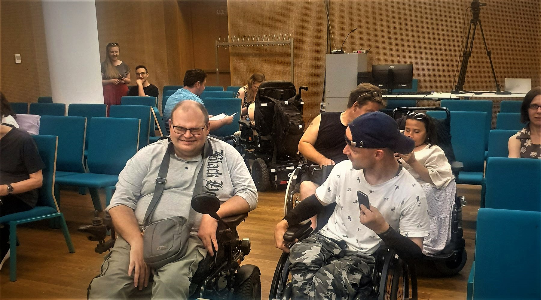 Dwaj mężczyźni na wózkach inwalidzkich rozmawiają ze sobą podczas spotkania filmowego.