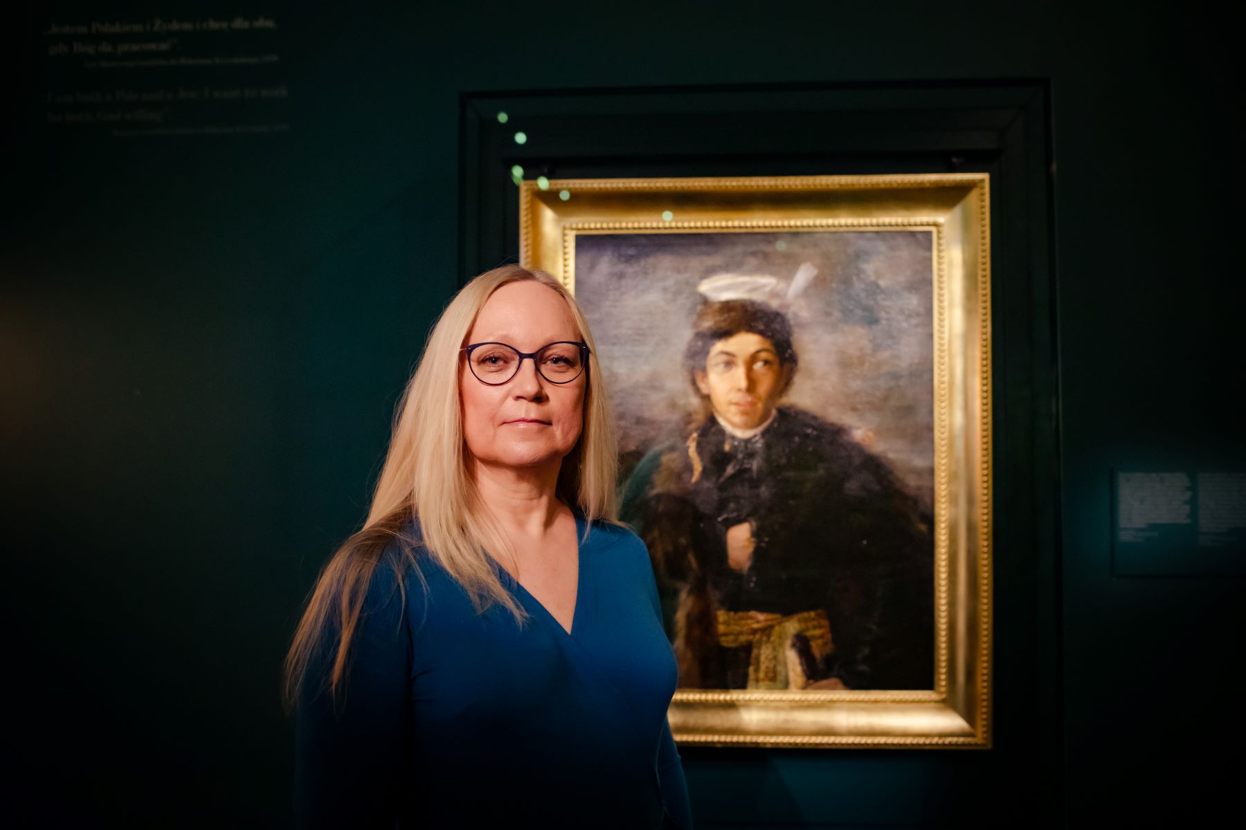 Przewodniczka Muzeum POLIN stoi przy obrazie Maurycego Gottlieba "Autoportret w stroju polskiego szlachcica".