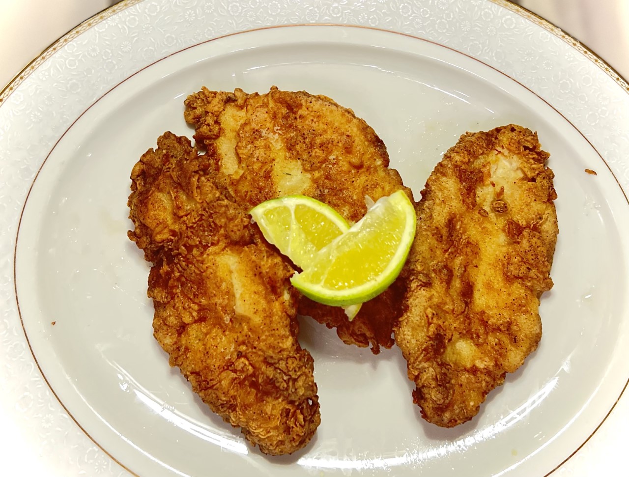 Three schnitzels on the plate. On the bottom there are slices of lemon.