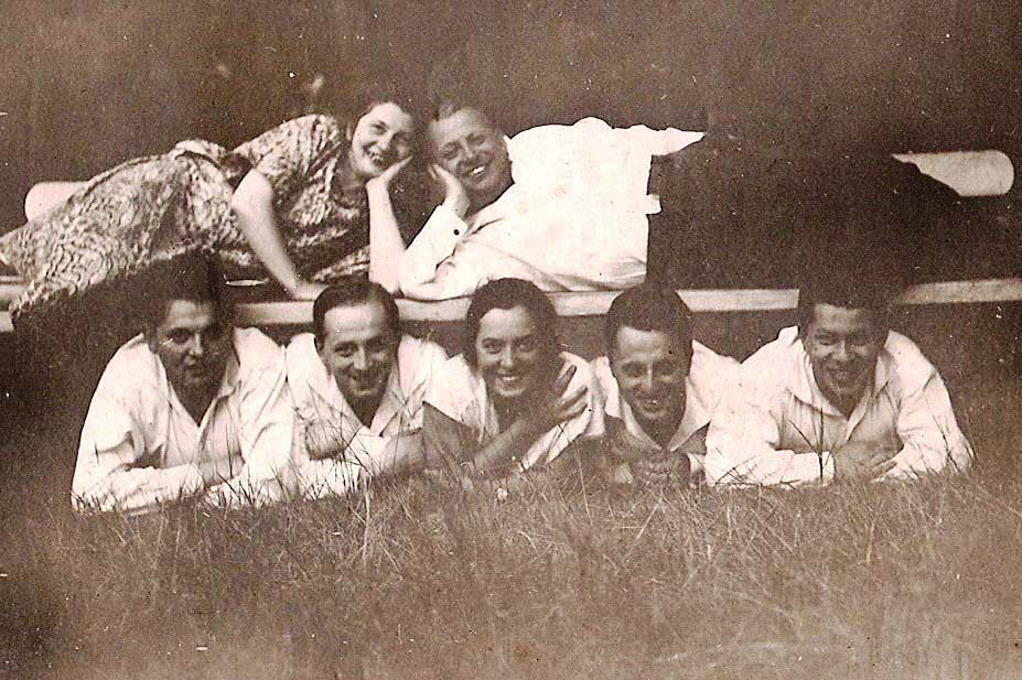 Rodzina Izaaka i Hadasy Hamburgów z Warszawy - kobieta i mężczyzna leżą na ławce, na trawie zaś kobieta i czterej mężczyźni.