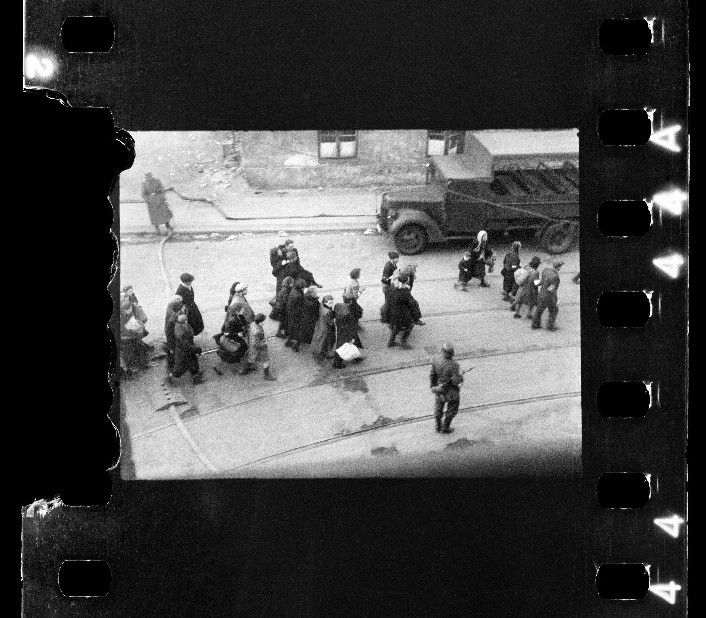 Warszawska ulica. Żydzi prowadzeni przez Niemców na Umschlagplatz. / Warsaw Street - the Jews on their way to Umschlagplatz. Around them there are German soldiers.