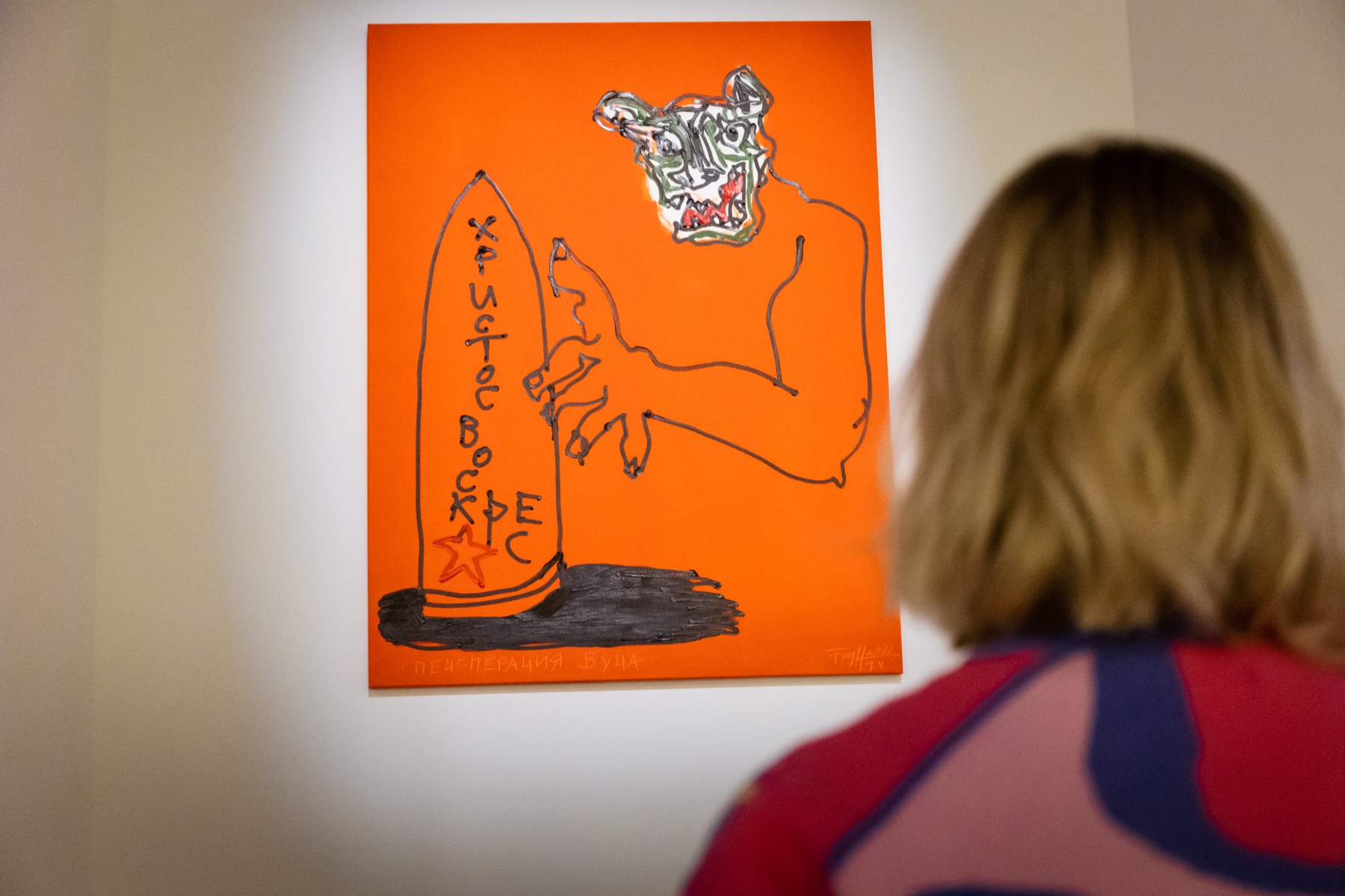 Kobieta stoi przed jednym z obrazów z serii "Bucza" Andrzeja Fogtta prezentowanym w POLIN.