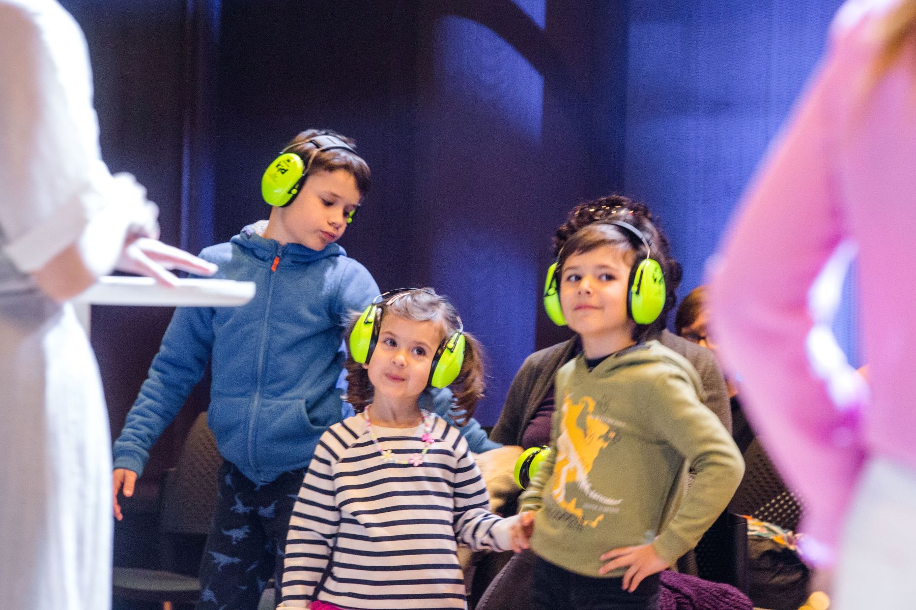 Troje dzieci w zielonych słuchawkach na uszach.
