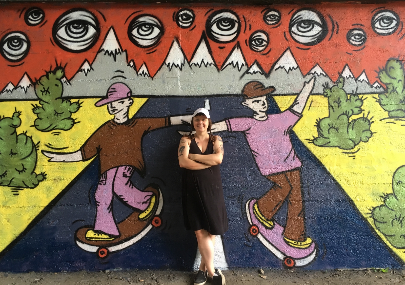 Dorota Cieślik (Miss Dorys) stoi przy kolorowym muralu z założonymi na siebie rękami.