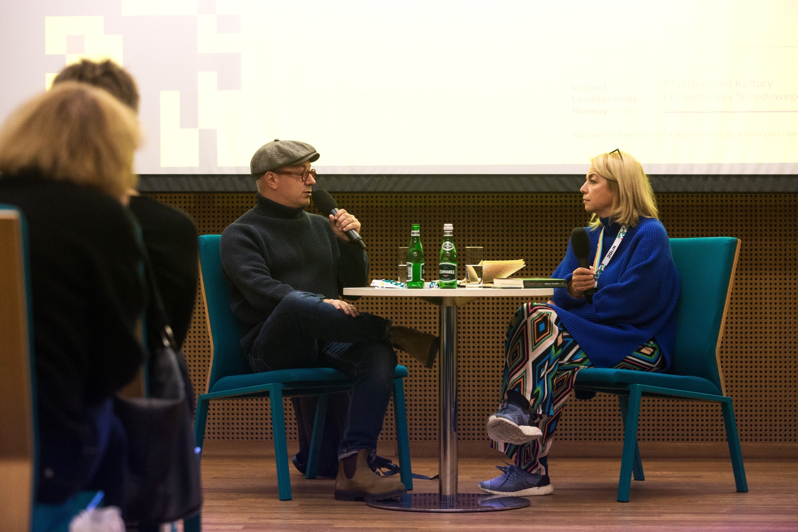 Joanna Fikus i Mikołaj Grynberg siedzą przy stoliku podczas spotkania z pisarzem w ramach kongresu Żydowskie Dziedzictwo Kulturowe.