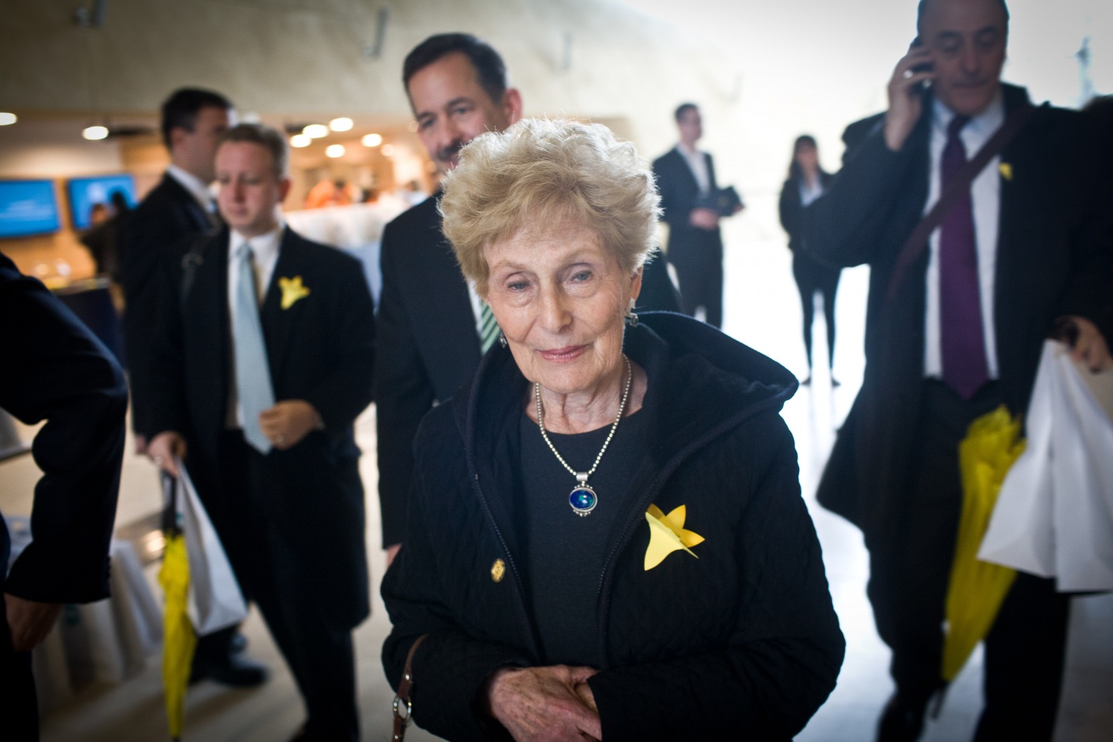 Starsza kobieta w holu Muzeum POLIN podczas akcji Żonkile 2013. Do ubrania ma przypięty papierowy żonkil - symbol akcji.