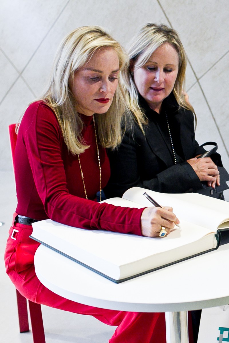 Dwie kobiety siedzą obok siebie, jedna z nich wpisuje się do księgi pamiątkowej w Muzeum POLIN.