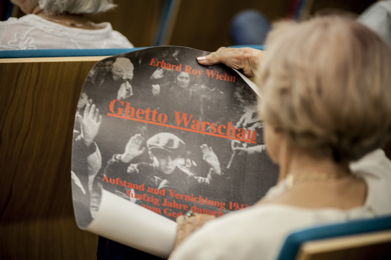 Kobieta ogląda plakat z napisem Ghetto Warschau.