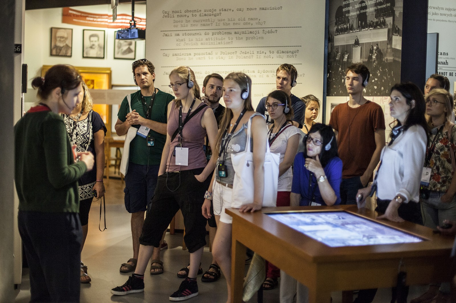 Grupa młodych ludzi zwiedza z przewodnikiem wystawę stałą w POLIN.