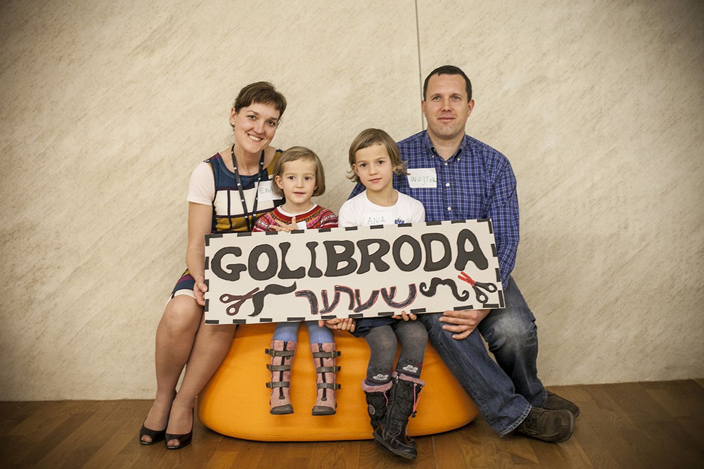 Czteroosobowa rodzina pozuje do zdjęcia z tabliczką z napisem Golibroda.