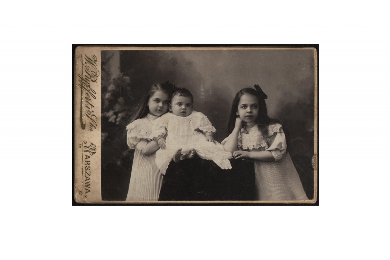 Czarno-białe zdjęcie przedstawia troje dzieci - dwie dziewczynki i młodszego od nich chłopca.