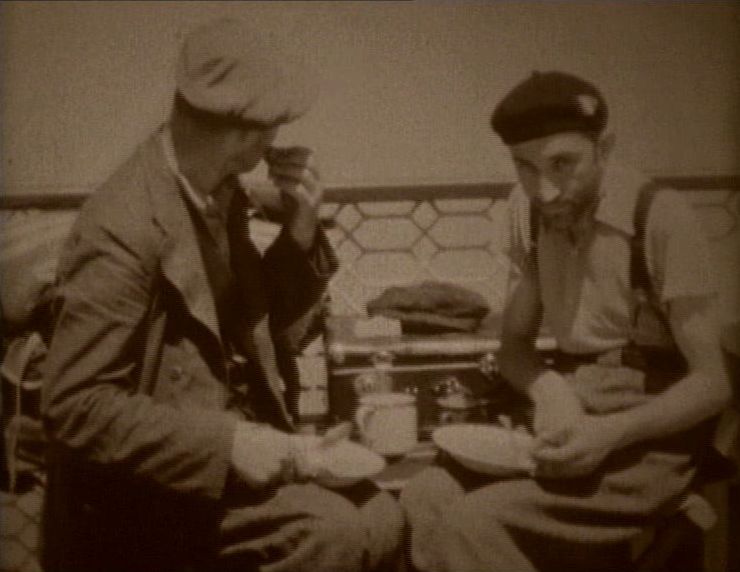 Dwaj mężczyźni w beretach siedzą przy stoliku. Kadr z filmu "Exodus przez Dunaj".