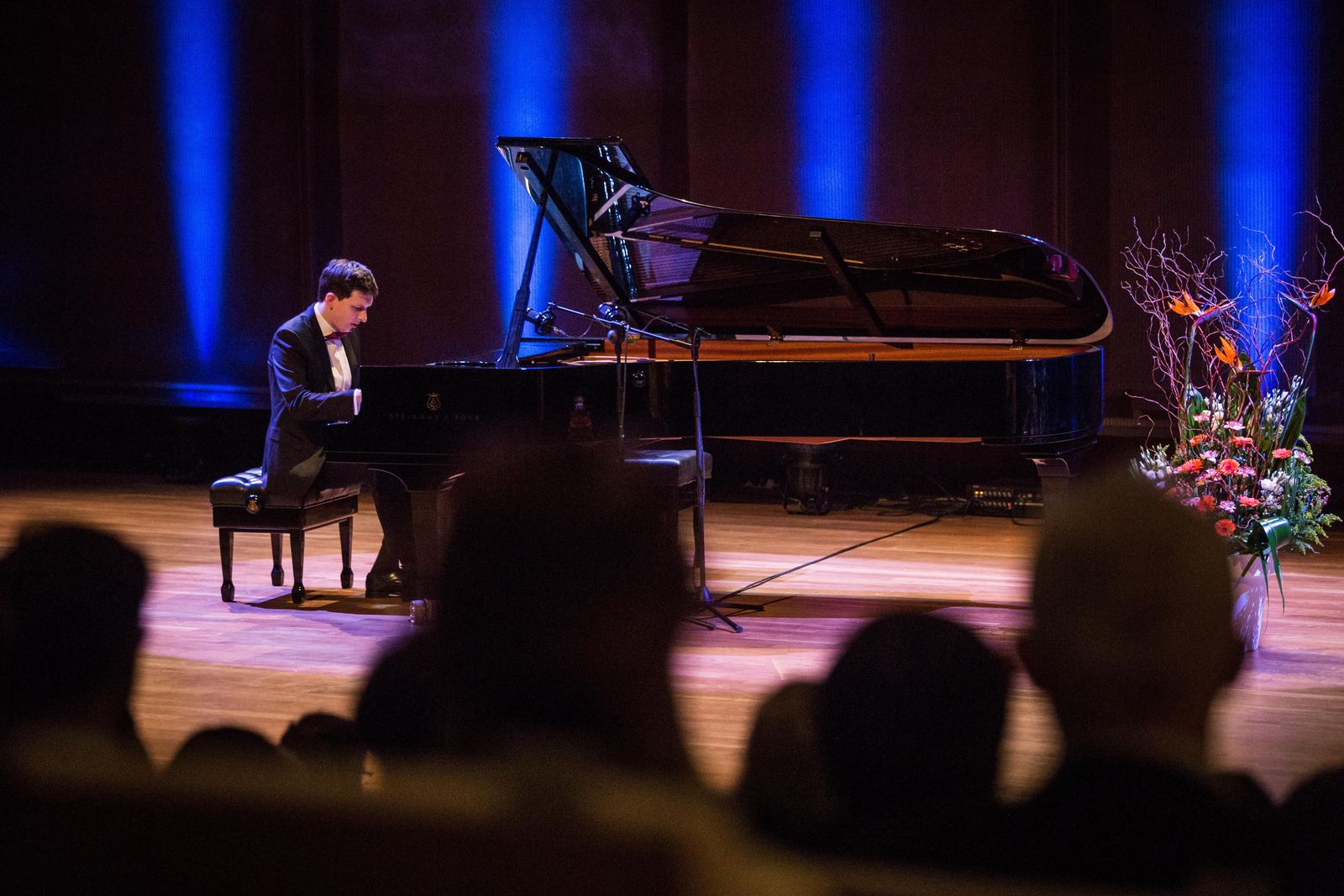 Na scenie stoi fortepian, przy nim pianista gra utwór. Scena podświetlona na niebiesko.