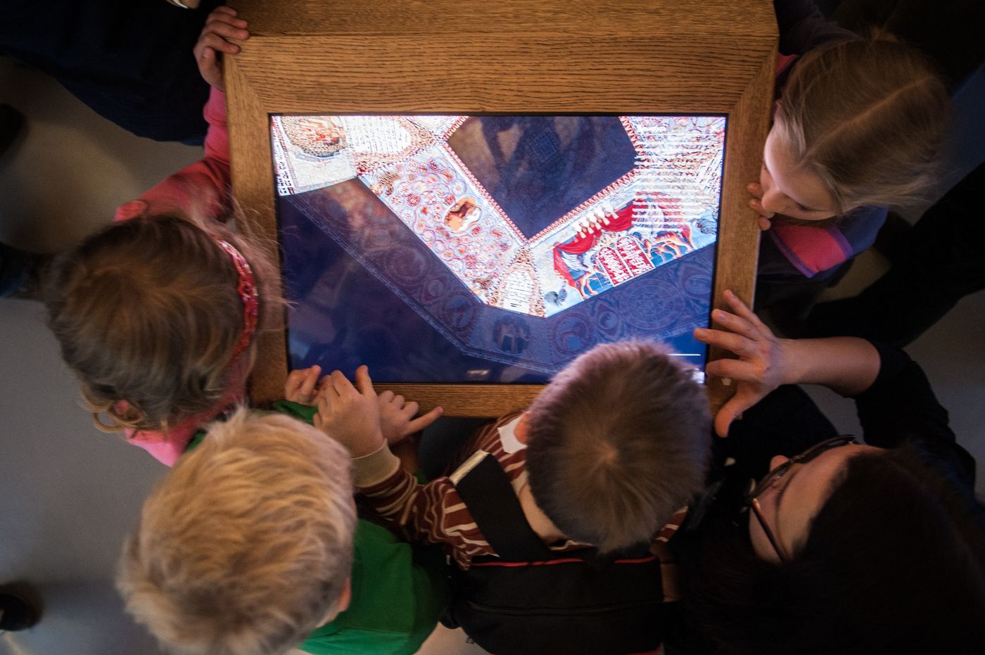 Kilkoro dzieci zgromadzonych wokół ekranu multimedialnego.