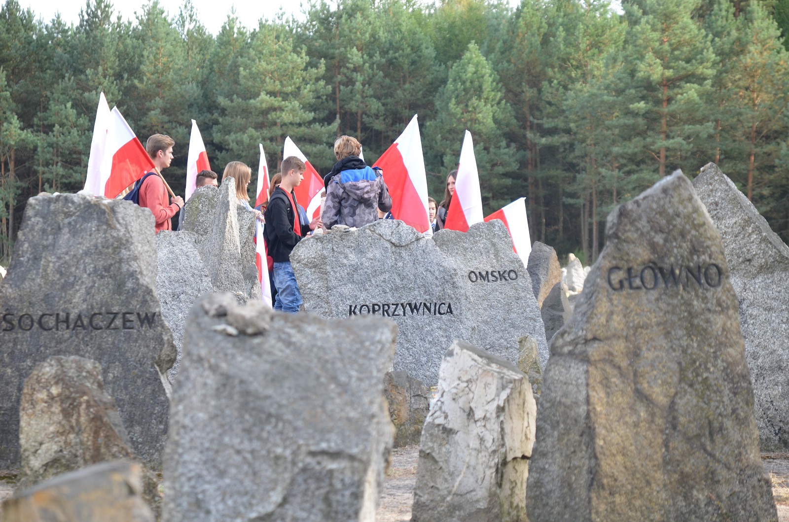 Jesteśmy razem - pamięci ofiar pomordowanych w Treblince. Nagrobki żydowskie. W tle ludzie z polskimi flagami.