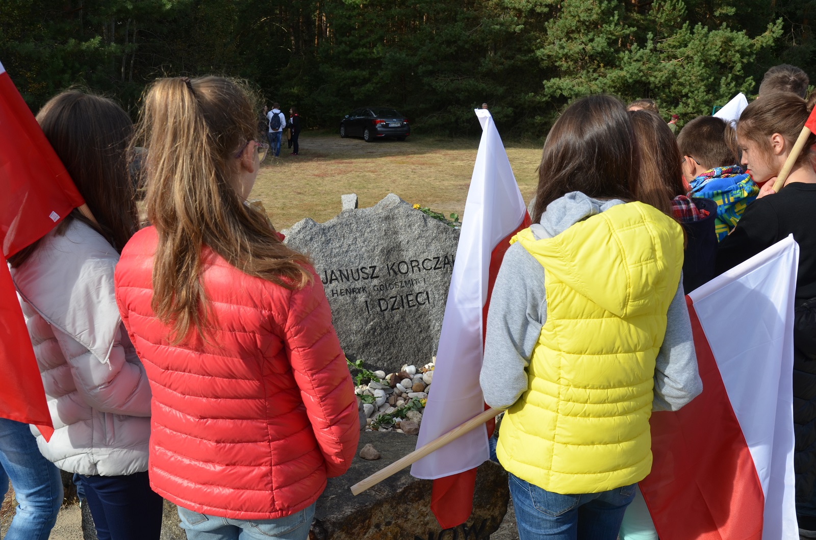 Jesteśmy razem - pamięci ofiar pomordowanych w Treblince. Grupa młodzieży stoi z flagami Polski przy jednym z nagrobków.
