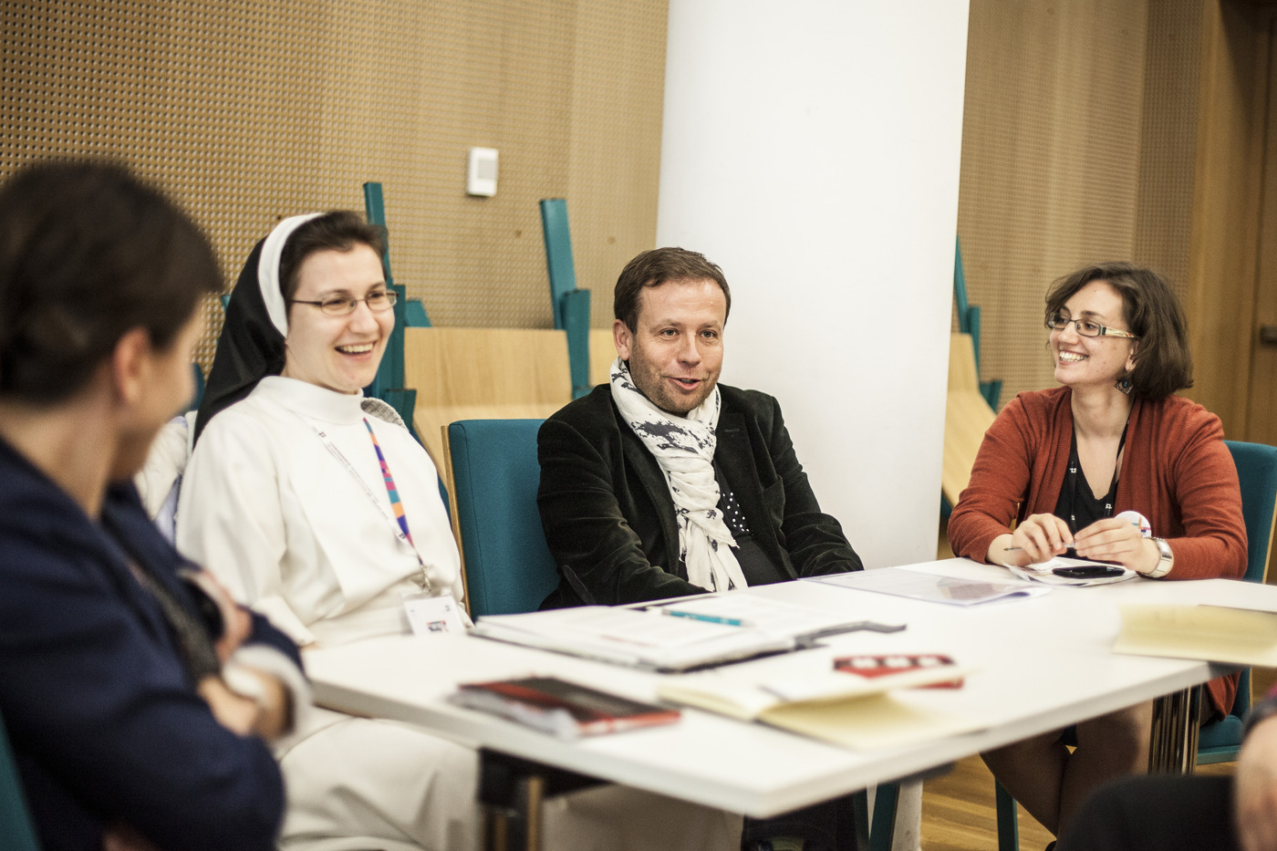 Cztery osoby, w tym siostra zakonna, siedzą przy stole podczas konferencji.