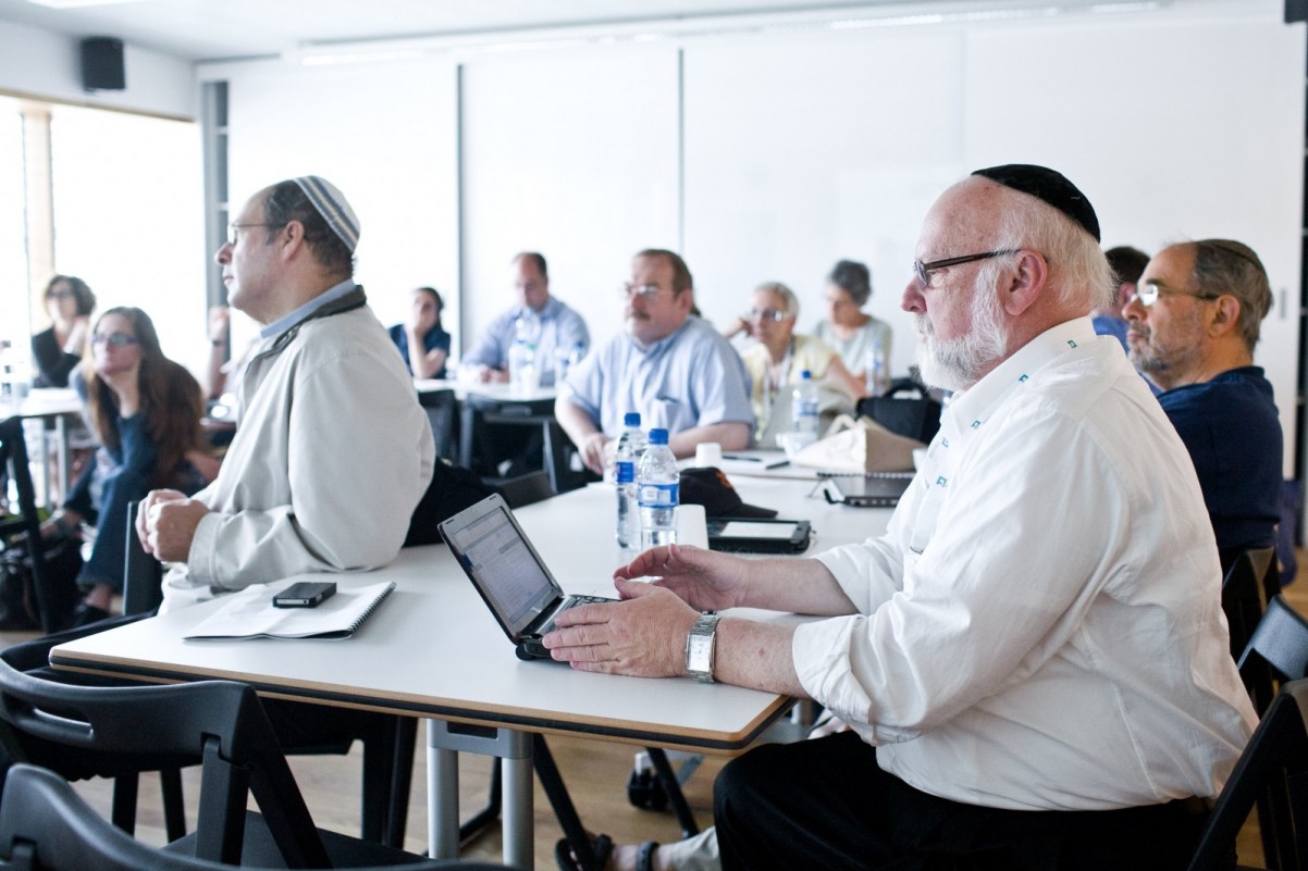 Grupa Żydów siedzi przy biurkach podczas spotkania.