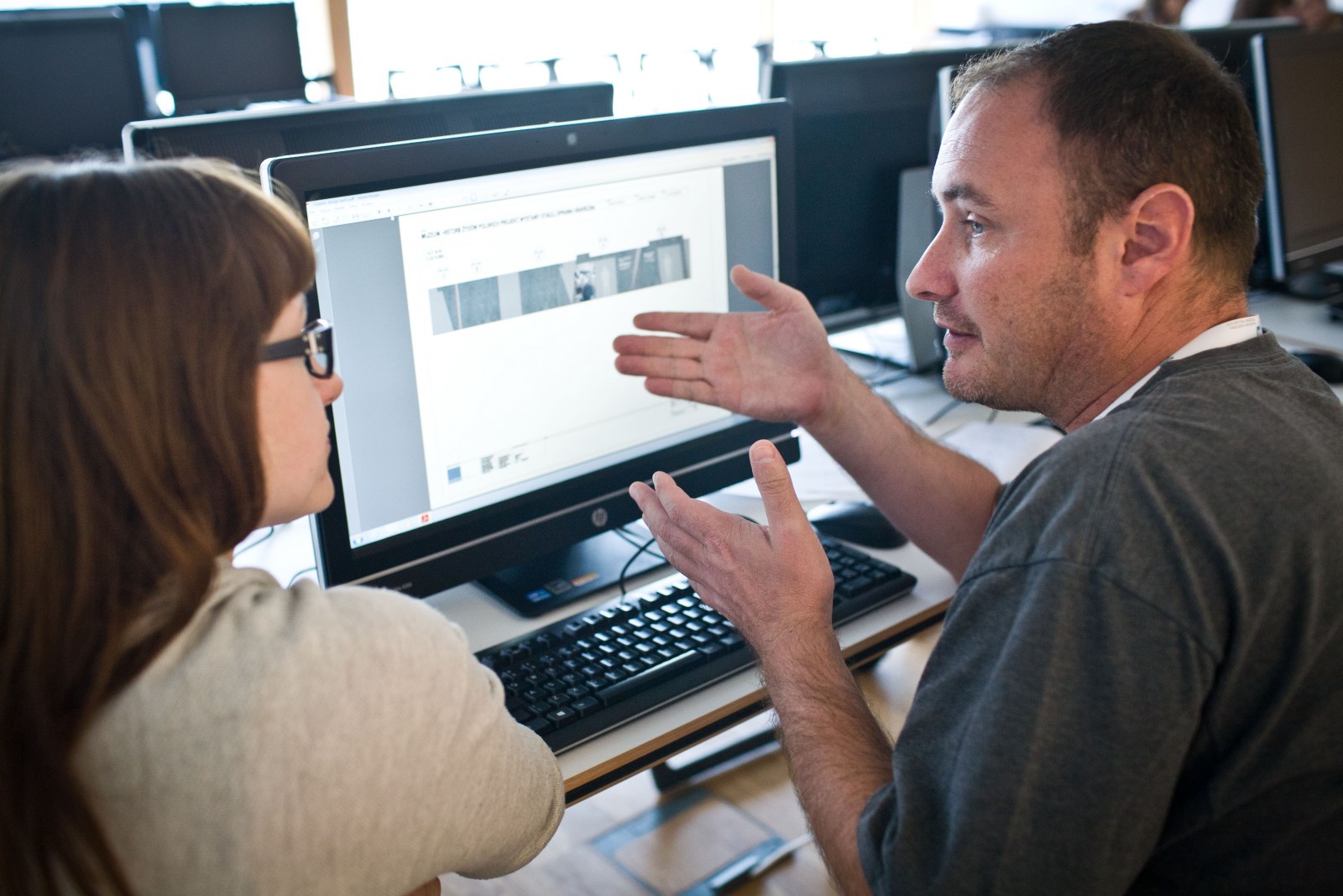 Mężczyzna pokazuje coś kobiecie na ekranie komputera.