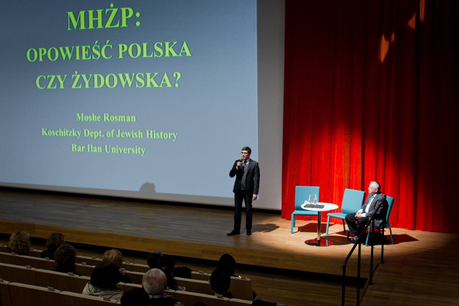 Mężczyzna stoi na scenie i wygłasza prezentację "MHŻP: Opowieść polska czy żydowska?".