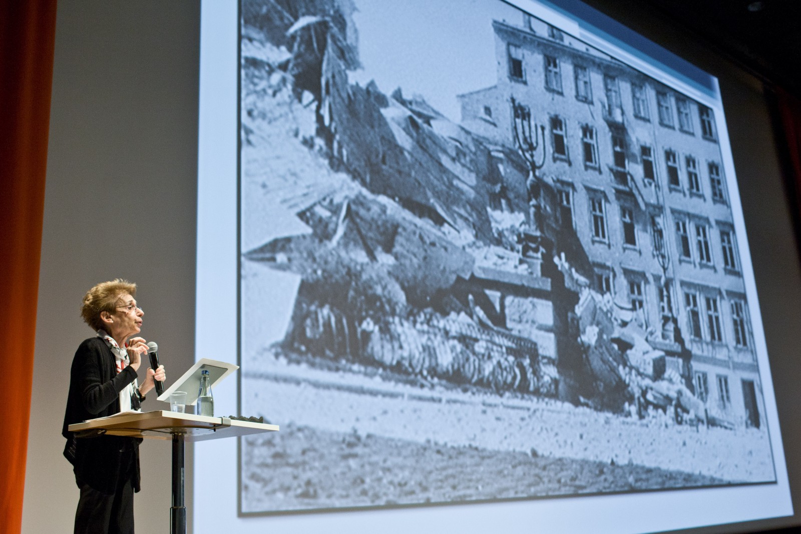 Rachel Brenner wygłasza wykład i prezentuje zdjęcie zburzonej kamienicy.