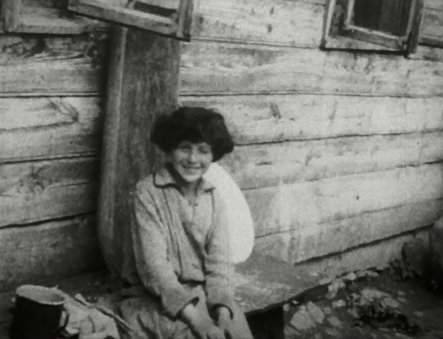 Kobieta siedzi na ławce przed domem - zdjęcie archiwalne.