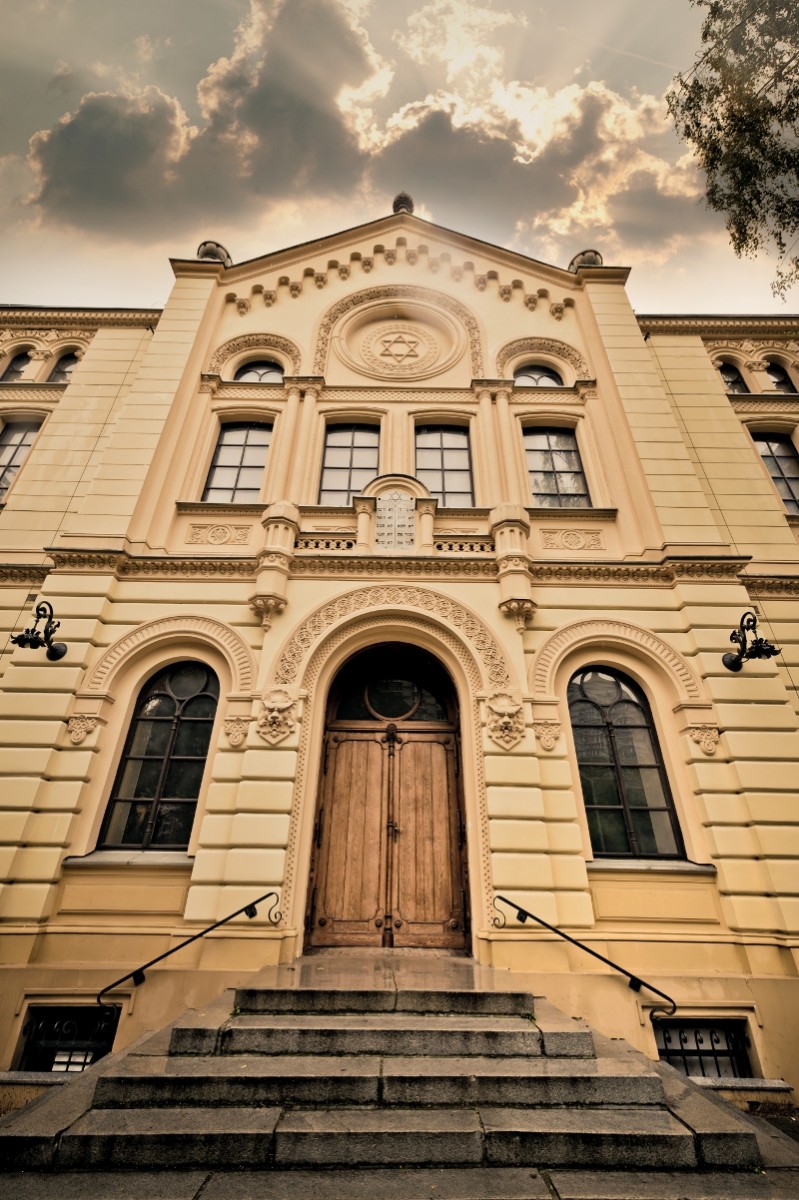 Frontowy widok z drzwiami i schodami Synagogi Nożyków na tle pochmurnego nieba