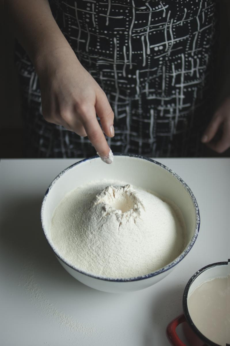 TISZ Festiwal: Finisaż. Na zdjęciu widać miskę przesianej mąki, która stoi na stole. W mące zrobione zagłębienie, na rozczyn drożdży - stoi on obok, przygotowany do wymieszania z mąką