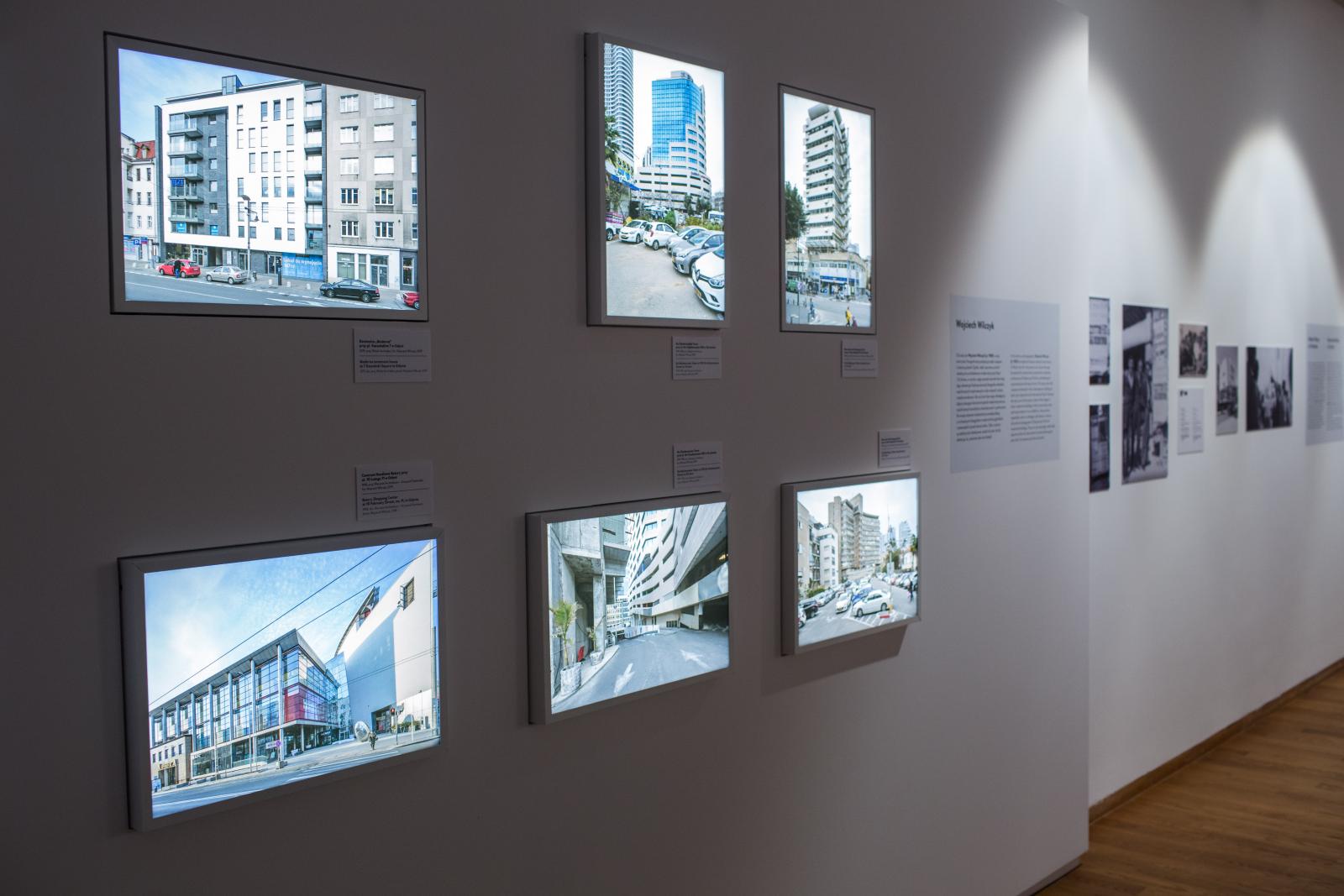 Wystawa czasowa "Gdynia - Tel Awiw" w Muzeum POLIN. Na zdjęciu 6 ekranów, wmontowanych w białą ścianę wystawową, na których wyświetlane są filmy, przedstawiające budynki modernistyczne z Gdyni i Tel Awiwu, wykonane przez Wojciecha Wilczyka