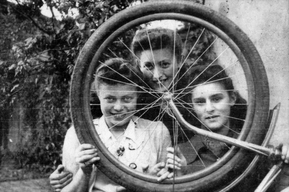 Matka z córkami patrzą przez koło rowerowe.