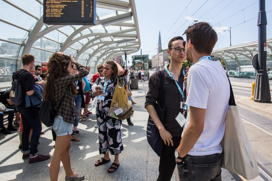 Uczestnicy programu podczas spaceru miejskiego po Warszawie - stoją pod wiatą przystanku tramwajowego