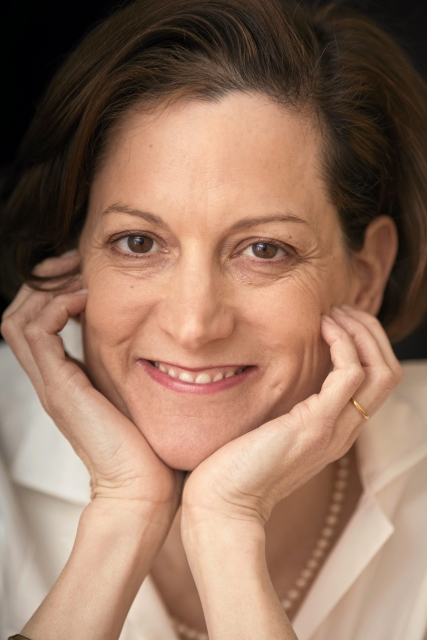 KObieta - szatynka (Anne Applebaum) - podpiera głowę na dwóch dłoniach. Uśmiecha się.