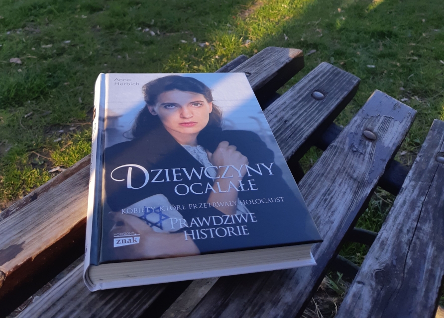 Okładka książki Anna Herbich "Dziewczyny ocalałe" - książka leży na ławce w parku.