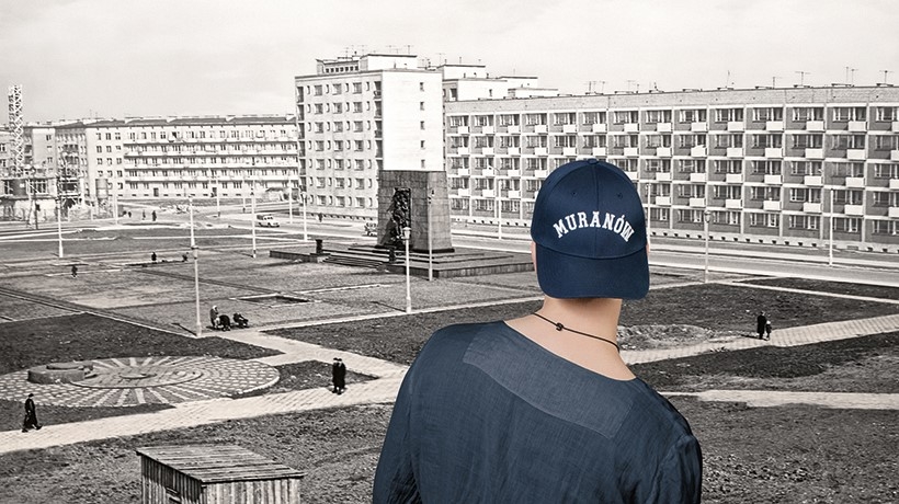 Młody współczesny mężczyzna spogląda na Muranów na archiwalne zdjęcie z lotu ptaka. Widzi m.in. Pomnik Bohaterów Getta