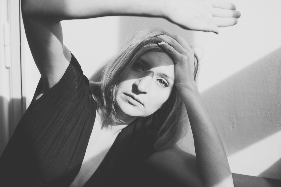 Czarno-białe zdjęcie kobiety (Barbara Klicka), która unosi ramię, osłaniając twarz przed słońcem