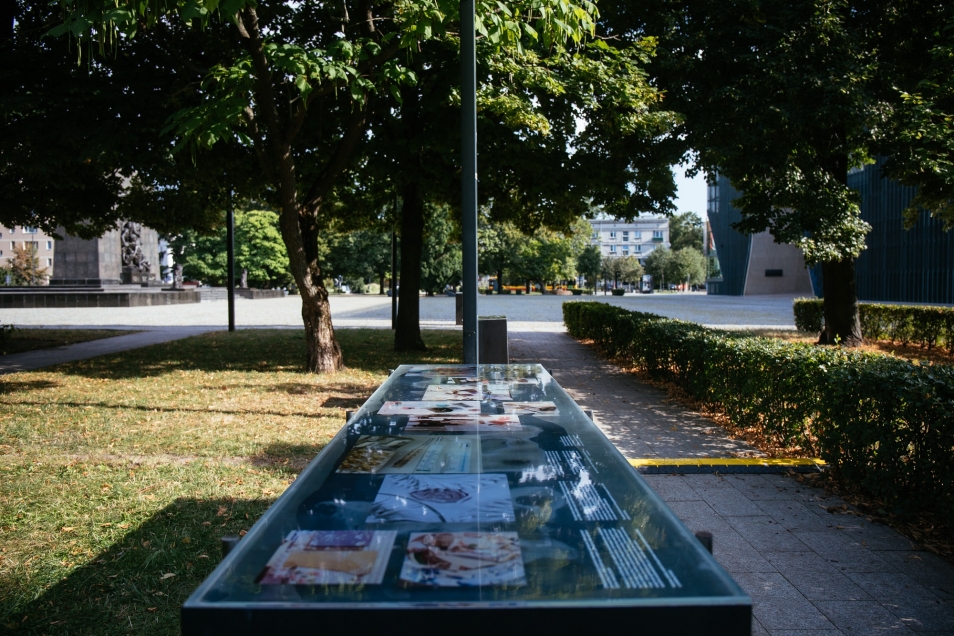 Gablota ze zdjęciami ustawiona w parku w otoczeniu Muzeum POLIN