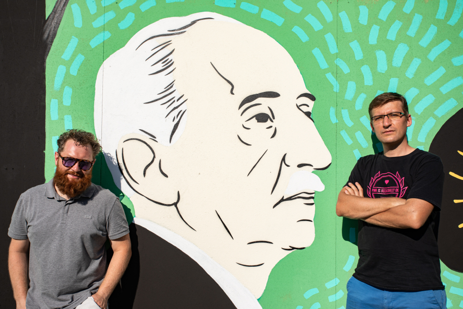 Prowadzący warsztaty na tle muralu z podobizną Bolesława Leśmiana.