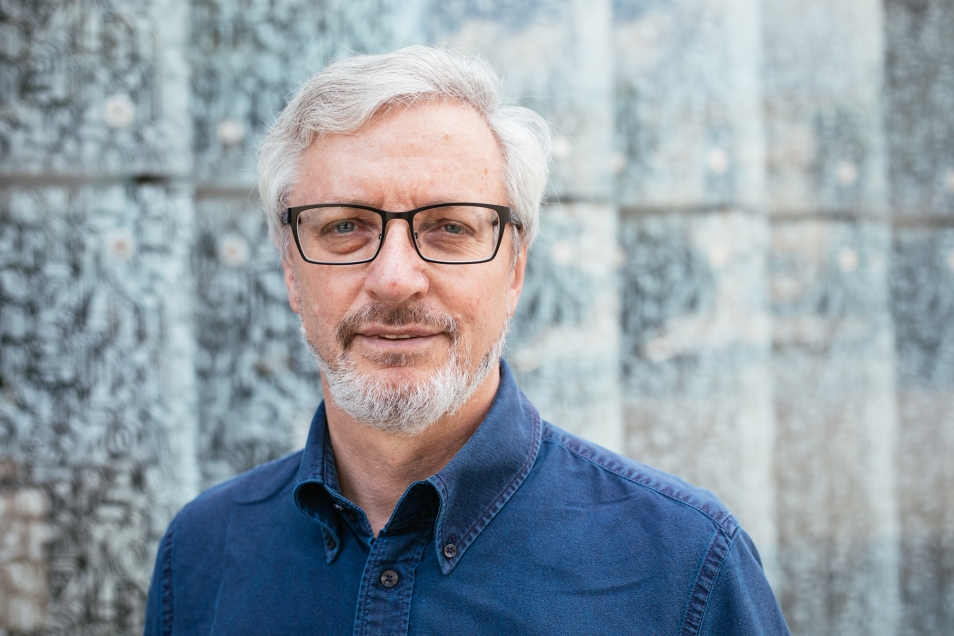 Mężczyzna (Jacek Leociak) na tle ściany szklanej Muzeum POLIN
