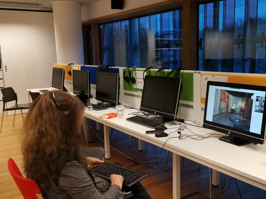 A line with the some computers. One woman is sitting behind them, she holds a keyboard.