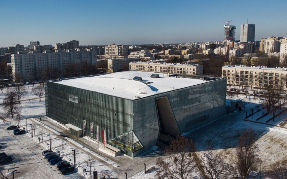 Budynek Muzeum POLIN w Warszawie, widziany z góry, w otoczeniu innych budynków osiedla Muranów. Zdjęcia zrobione zimą, dach muzeum oraz okoliczne chodniki i ulice pokryty jest śniegiem.