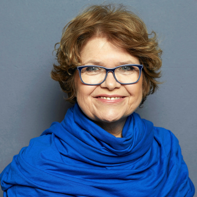 Anna Bikont - uśmiechnięta starsza brunetka w okularach z kwadratowymi oprawkami.