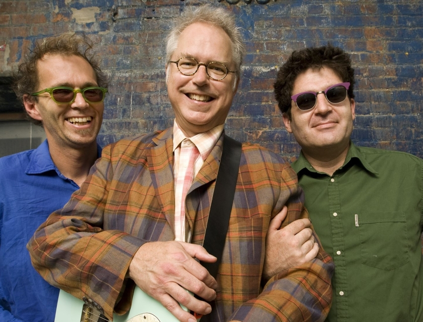 Trzej mężczyźni, członkowie Bill Frisell trio. Wszyscy uśmiechają się.