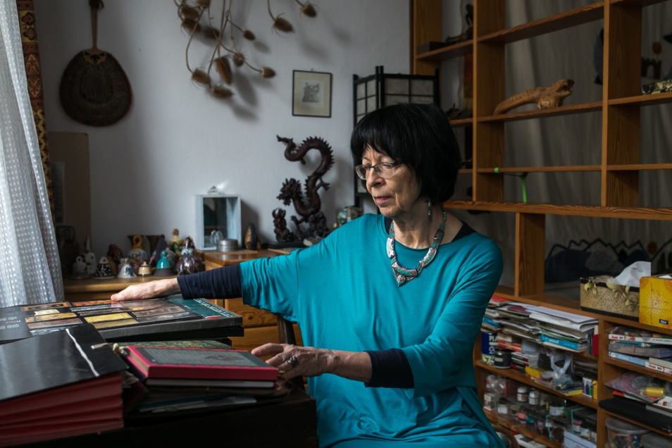 Monika Krajewska - starsza kobieta - w pokoju pełnym różnych pamiątek i dokumentów.