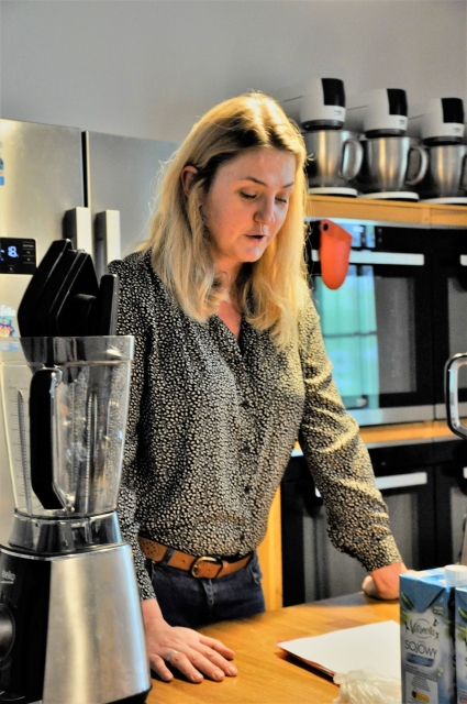 Alicja Szepierowska stoi przy stole, na którym znajdują się blender i mleko.
