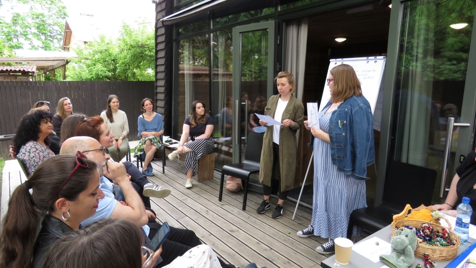 Uczestnicy seminarium podczas ćwiczeń – dwie osoby odgrywają scenkę dialogową, kilkanaście osób siedzi naprzeciwko nich.