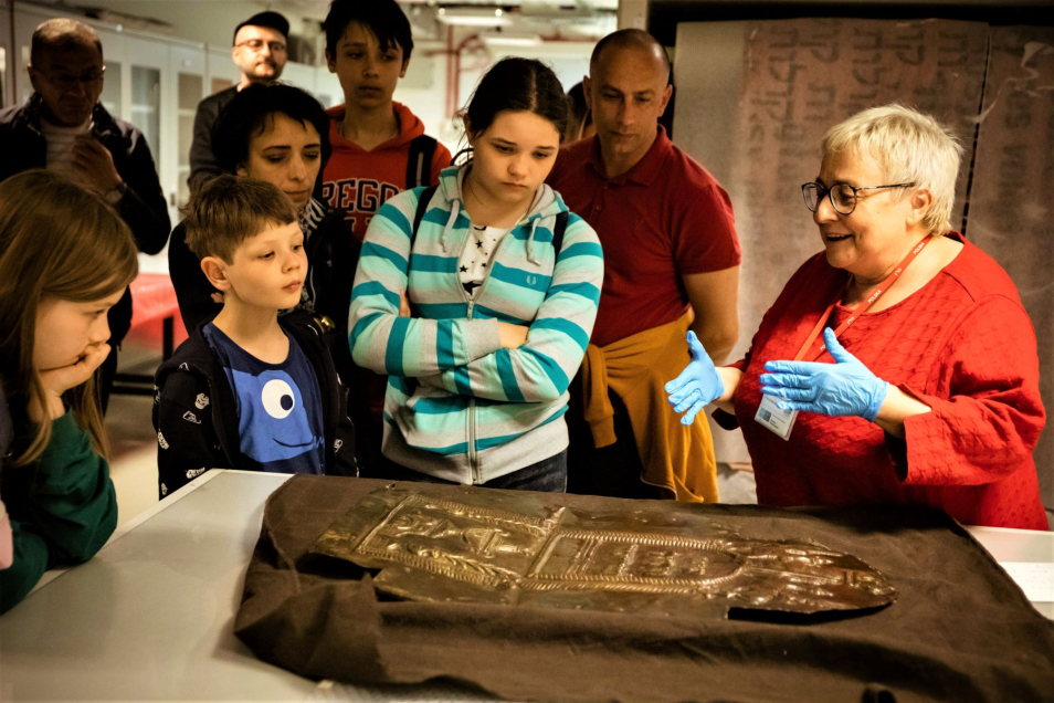 Główna kuratorka zbiorów Muzeum POLIN pokazuje grupie jeden z eksponatów podczas Nocy Muzeów 2022.