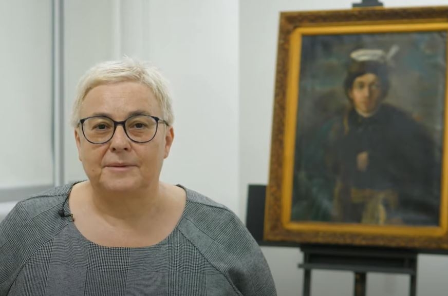 Renata Piątkowska na tle obrazu Maurycego Gottlieba "Autoportret w stroju polskiego szlachcica".